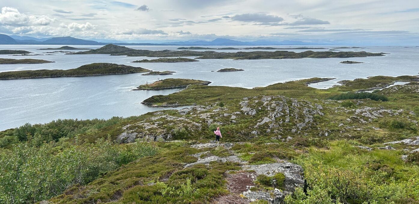 Jente går på sti ved fjorden. Foto