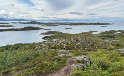 Jente går på sti ved fjorden. Foto