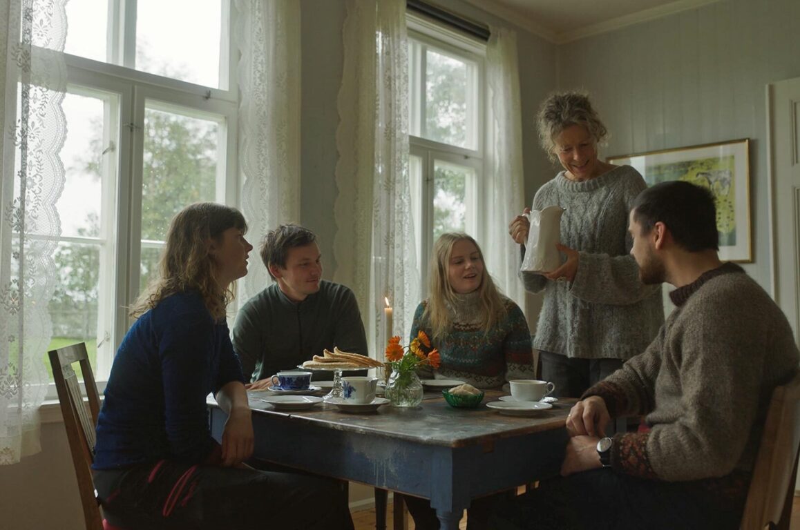 En gruppe mennesker sitter rundt et kafebord og får servering. Foto