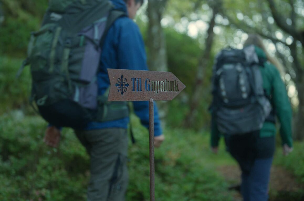 Folk på tur passerer et skilt med teksten "Gapahuk". Foto