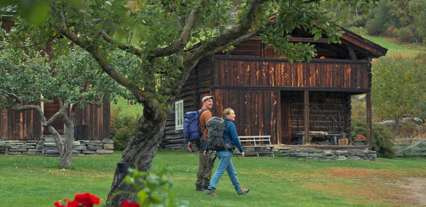 A man and a woman walking past a traditional farm