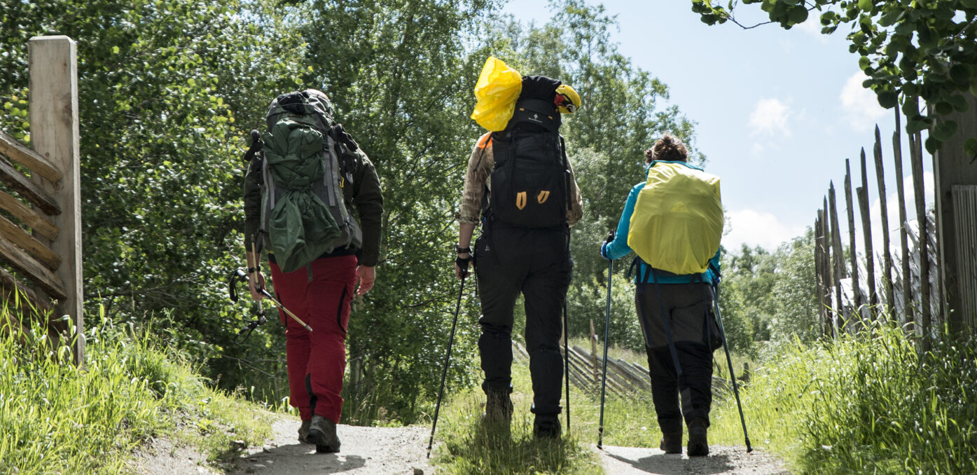 Three people with backpacks walking along a trail. Photo