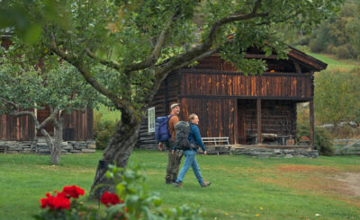 A man and a woman walking past a traditional farm