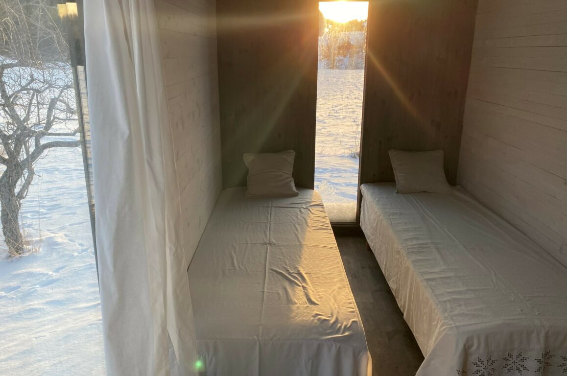 Innsiden av sponhuset med to sengeplasser og solstråler som skinner inn
